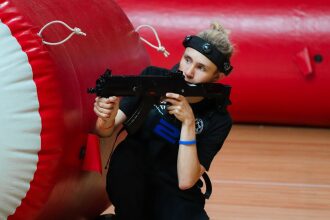 Игрок LASERWAR в низкой стойке с оружием у красного укрытия